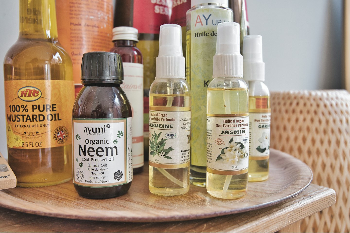 Bouteilles d'huiles naturelles variées disposées sur un plateau rond en bois.