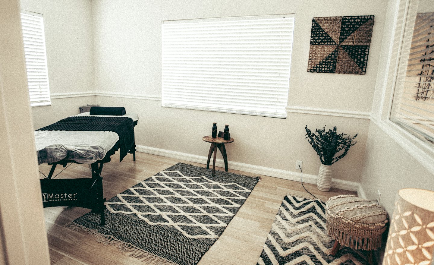 Salle de massage avec une table noire sur un tapis à motifs.